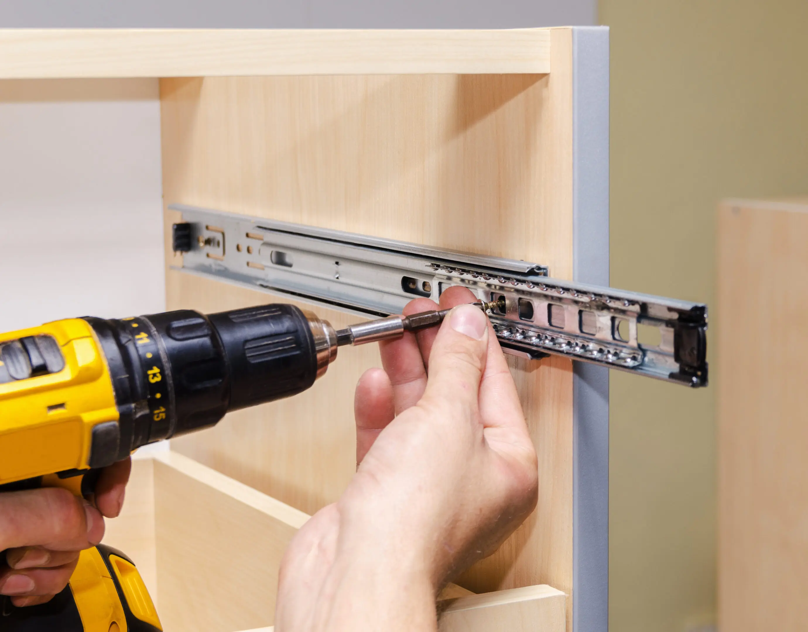 Assembling of furniture closeup Installing drawer slide with power drill.