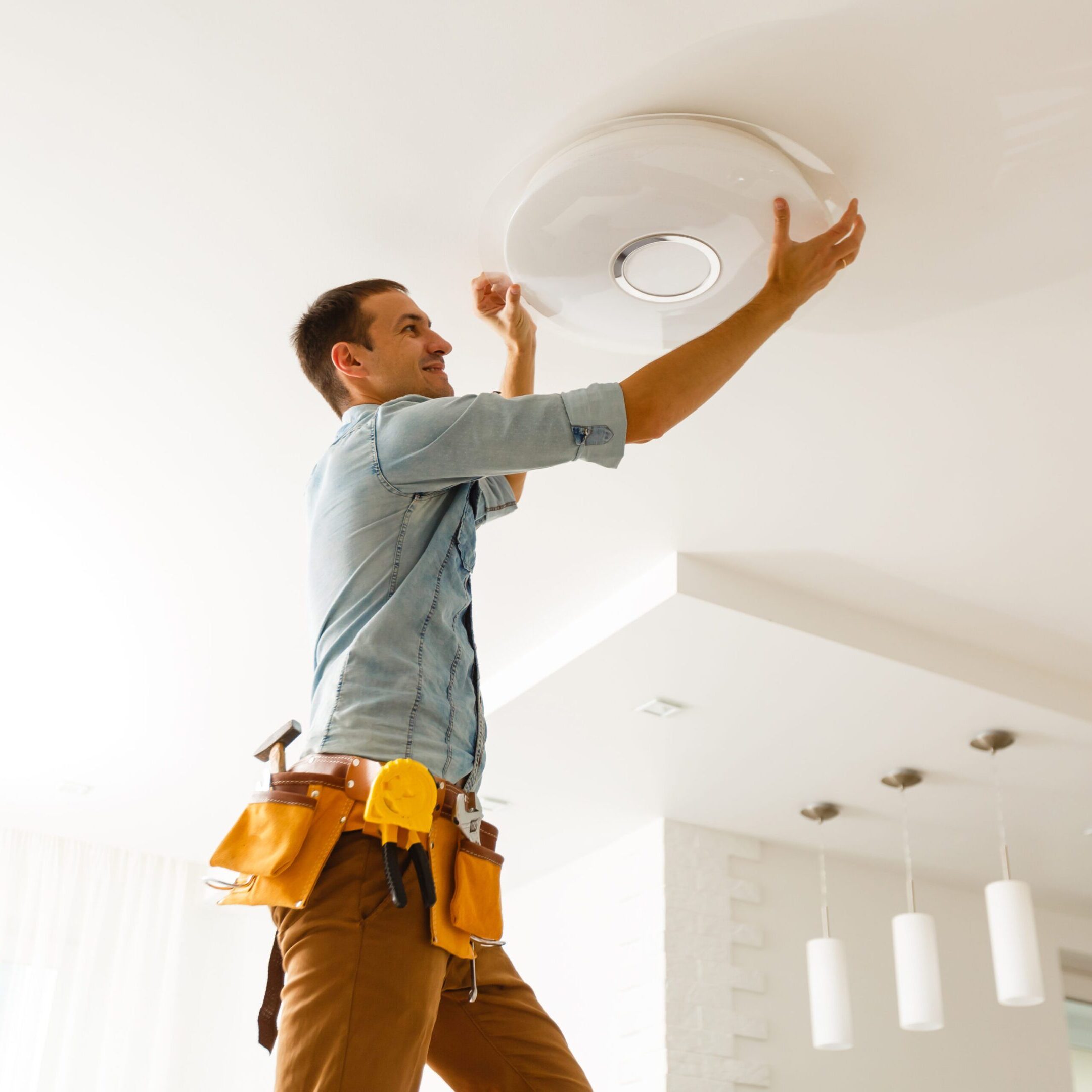 Electrician is installing and connecting a lamp to a ceiling. Man installing a ceiling light fixture.